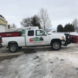 white pickup truck with snow plow attachment.